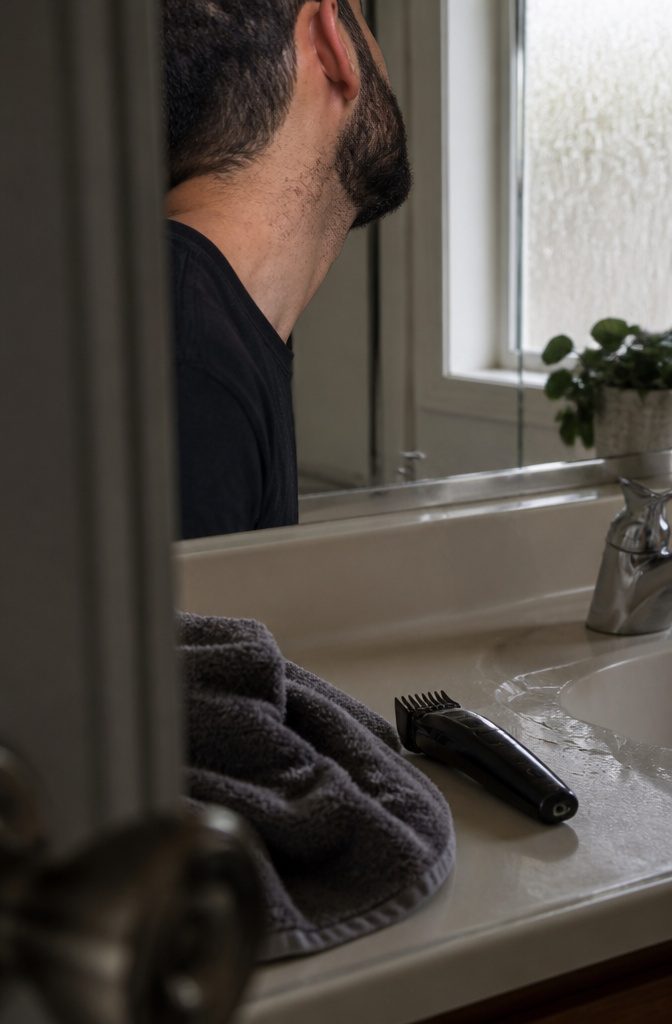 Man looking down at returning neck stubble beneath a high beard line