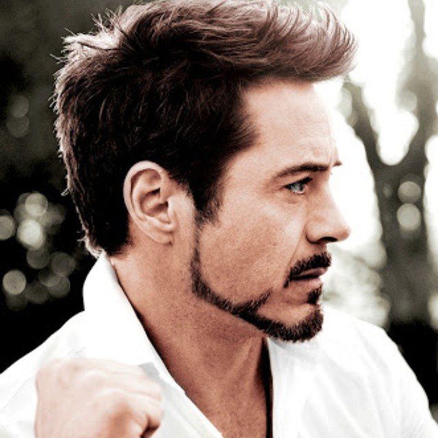 Man with a Balbo beard and brown hair wearing a white collared shirt.