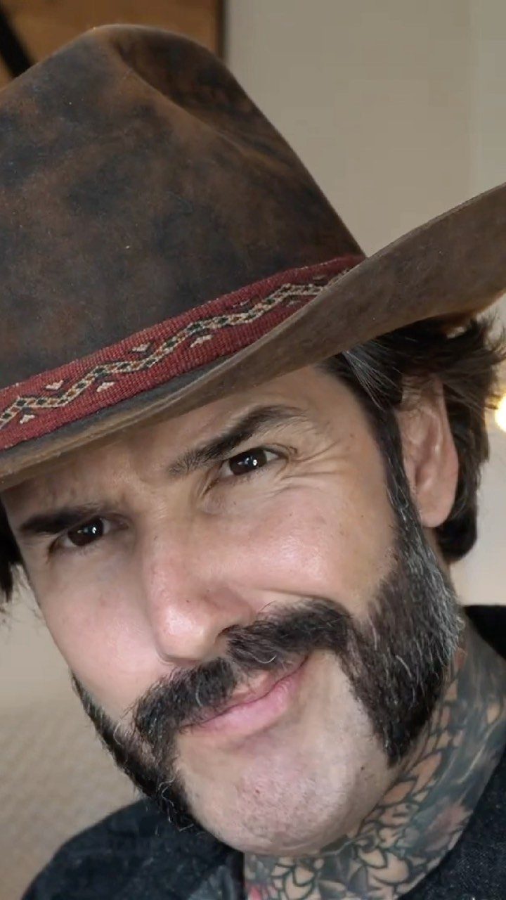 Man with a thick handlebar mustache and full beard wearing a brown cowboy hat