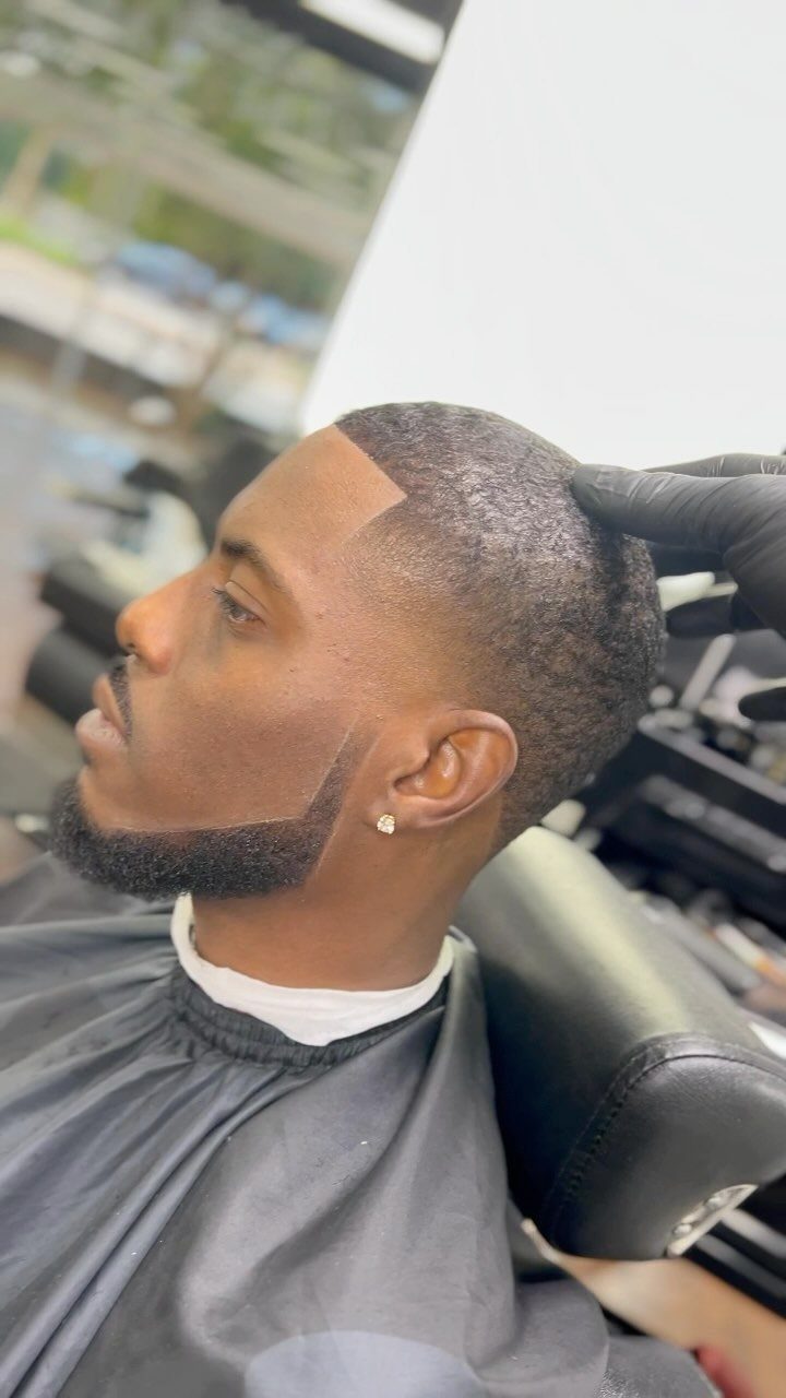 Man with a groomed chin strap beard and short fade haircut in barber chair