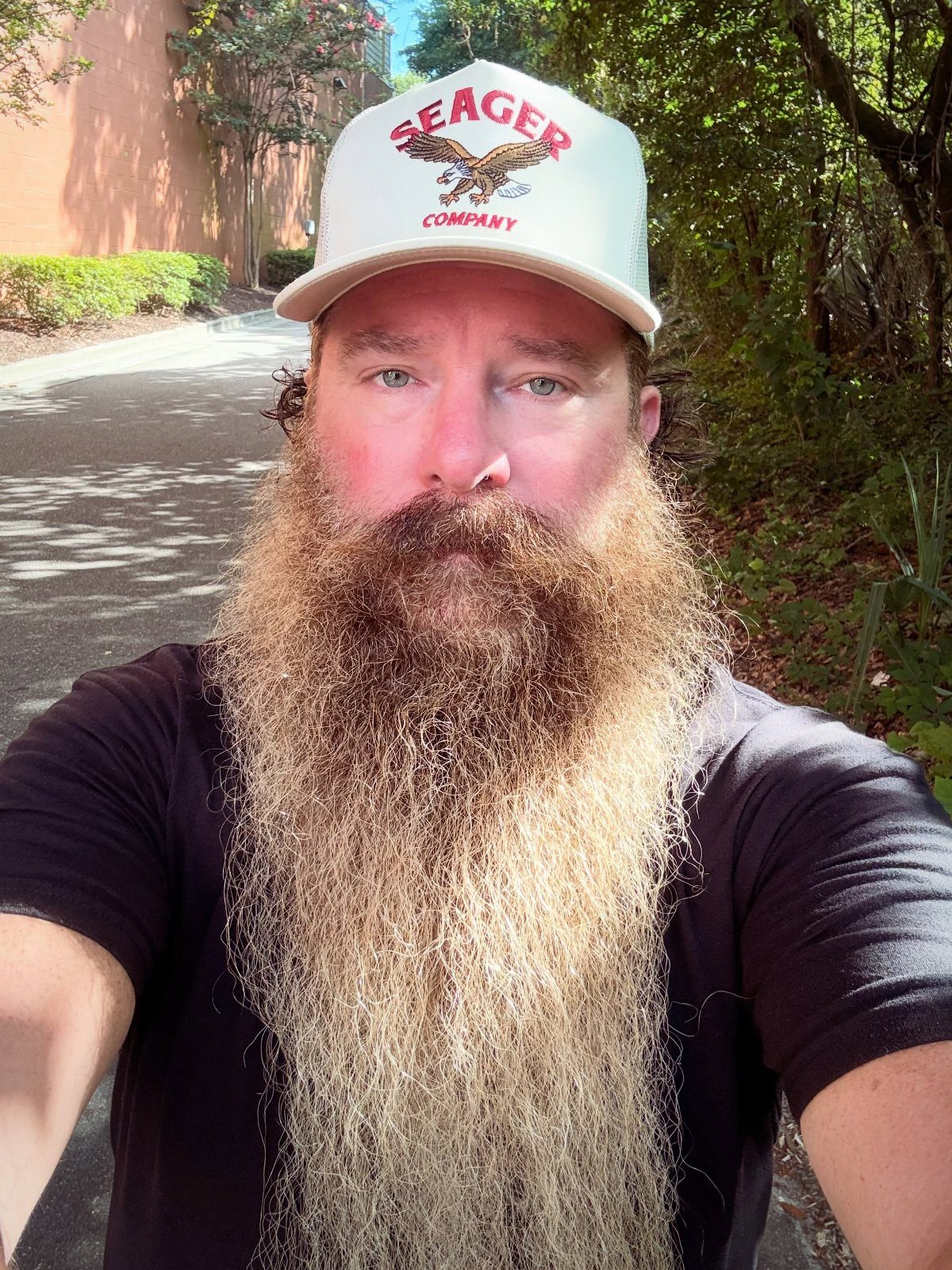 Man with a very long full beard wearing a white baseball cap