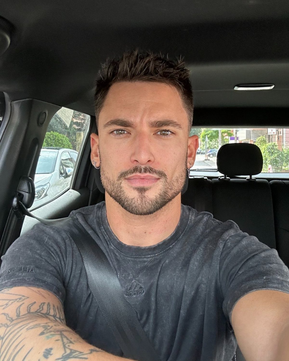 Man with a groomed beardstache and short hair sitting in a car