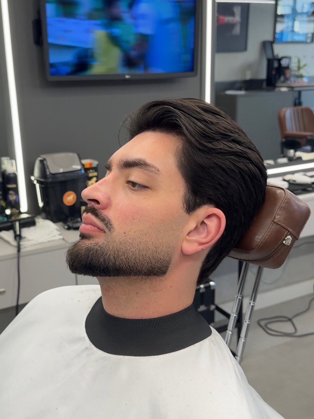 Man with a groomed short corporate beard sitting in a barber chair