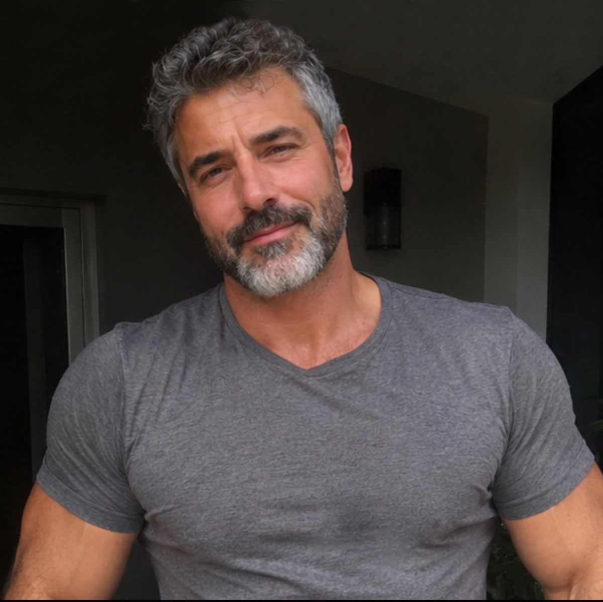 Man with grey hair and a well-groomed heavy stubble beard wearing grey shirt.