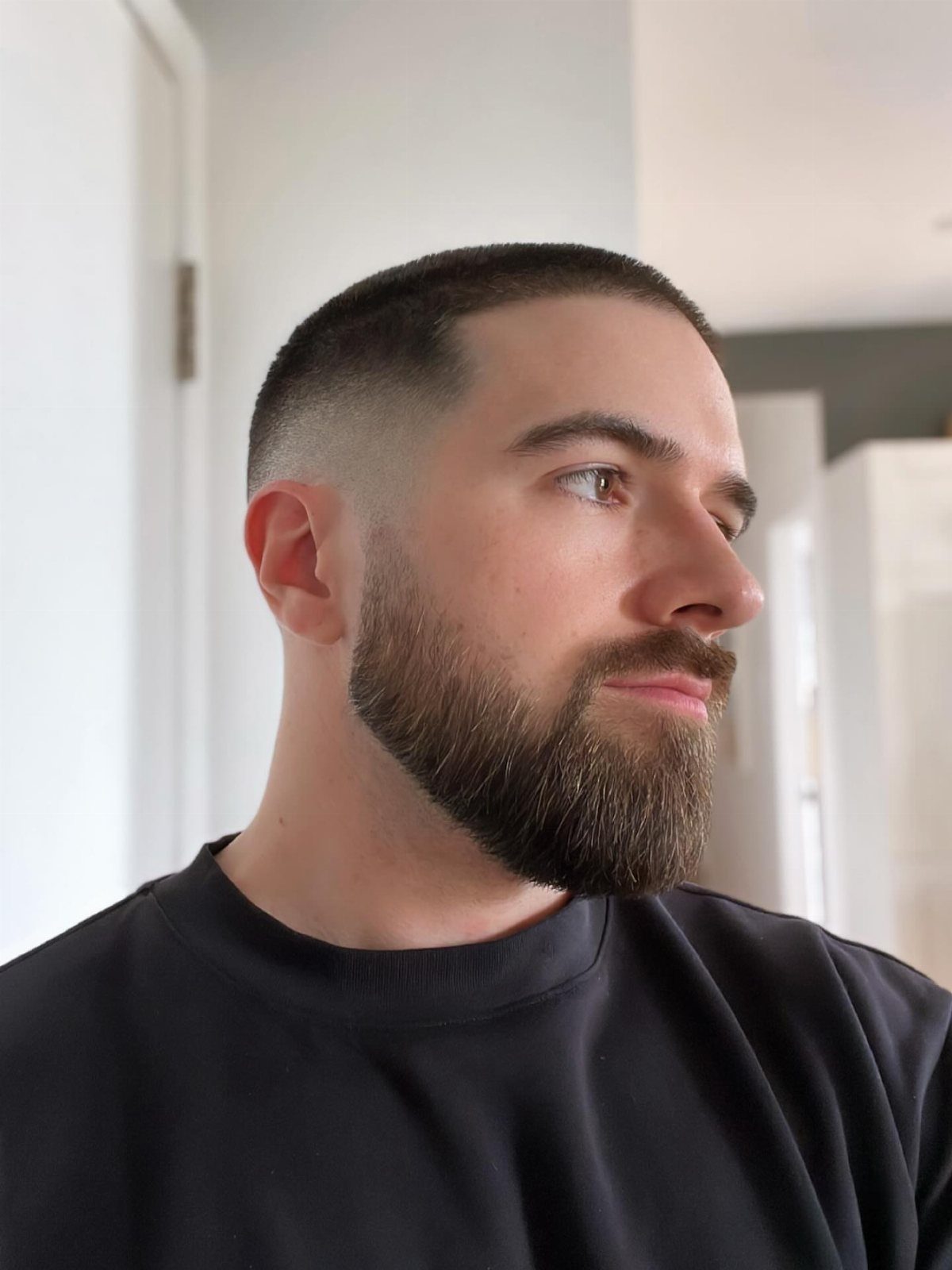 Man with a high skin fade buzz cut and a full groomed beard.