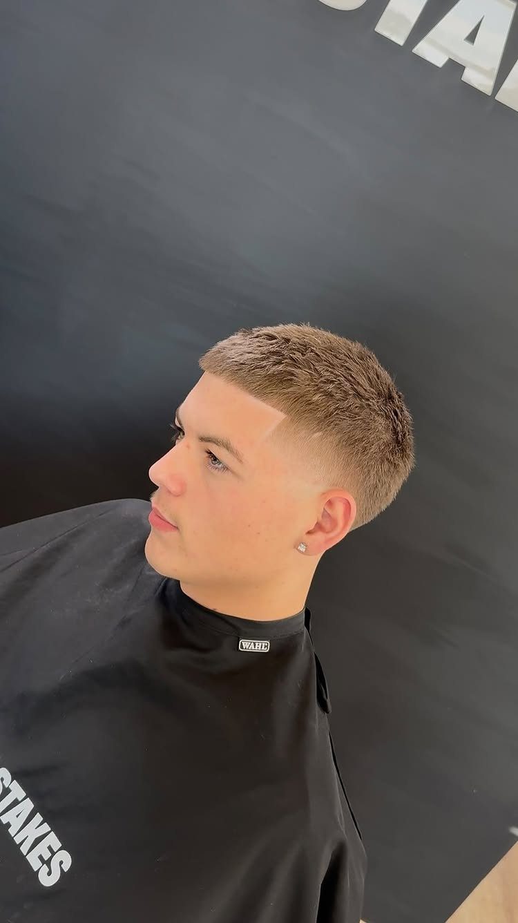 Young man with a high skin fade buzz cut wearing a black cape.
