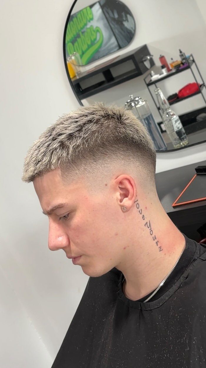 Man with a textured buzz cut and high skin fade in a barbershop.