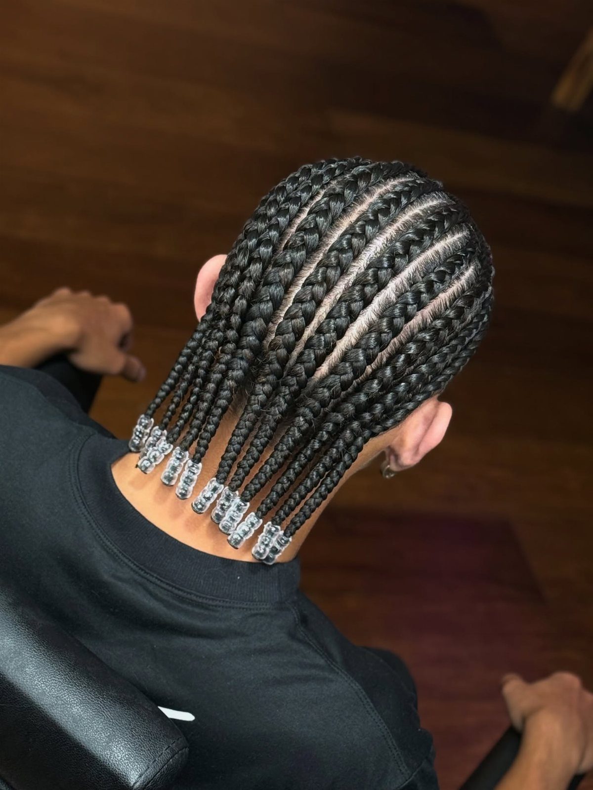 Man with straight-back cornrows featuring silver beads at the ends of the braids.