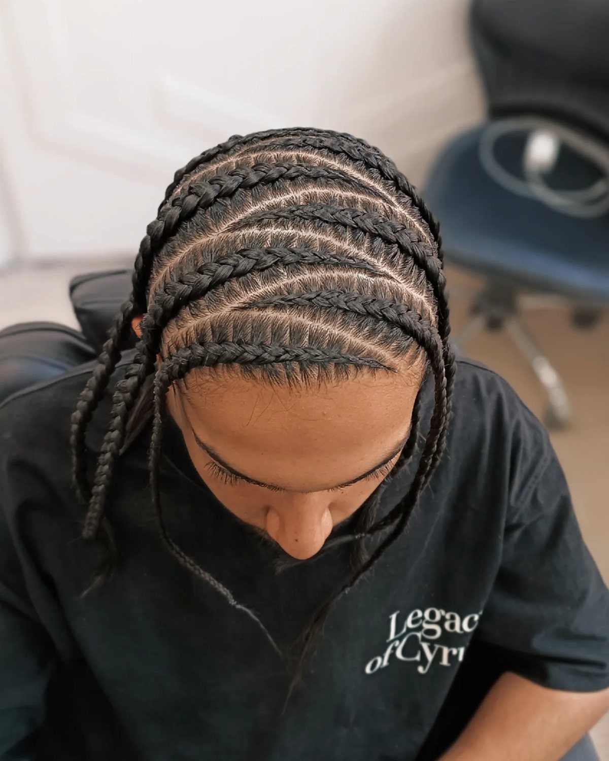 Man with neat straight-back cornrows extending from the forehead to the back.