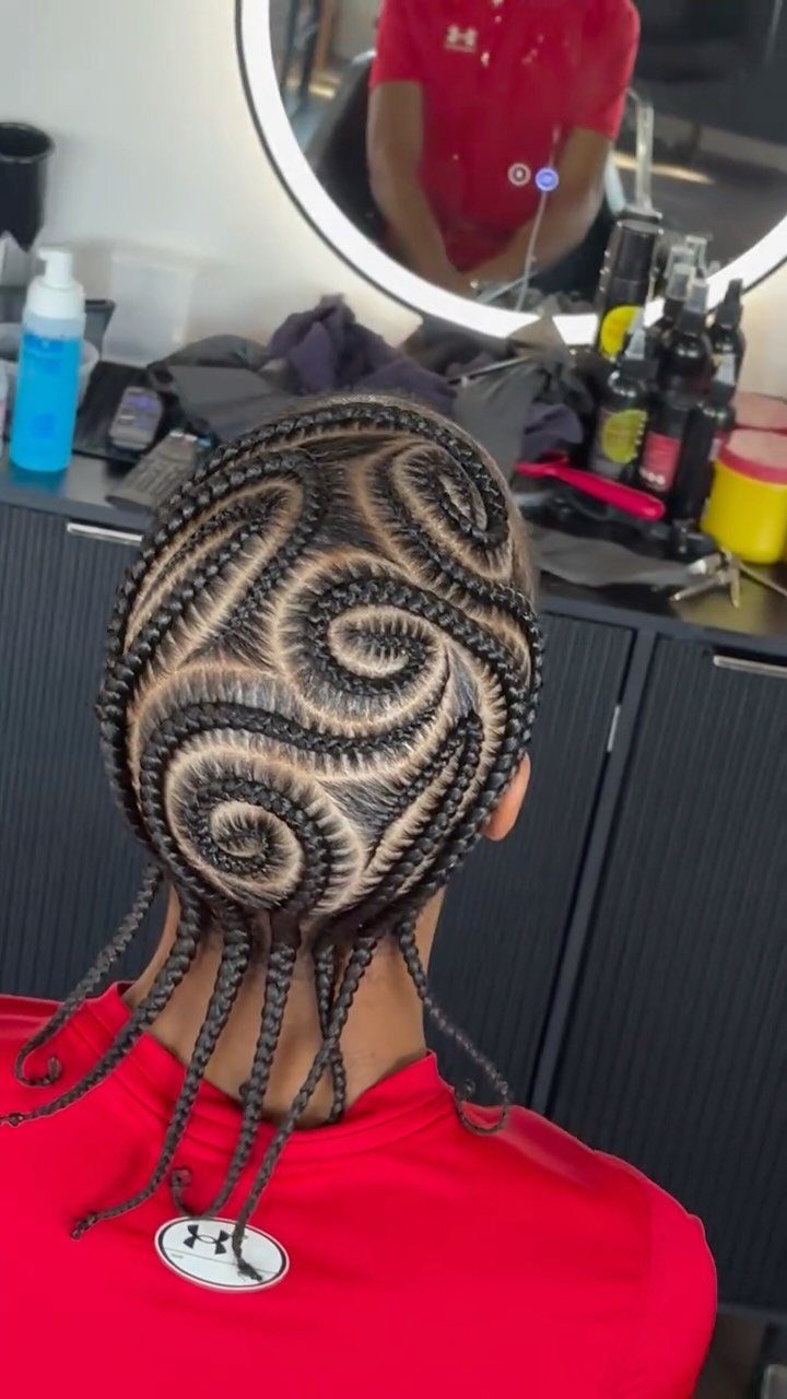 Intricate swirling cornrow patterns on a person's head in a salon setting.