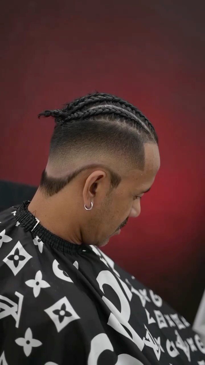 Man with cornrow braids on top and a high skin fade on sides.