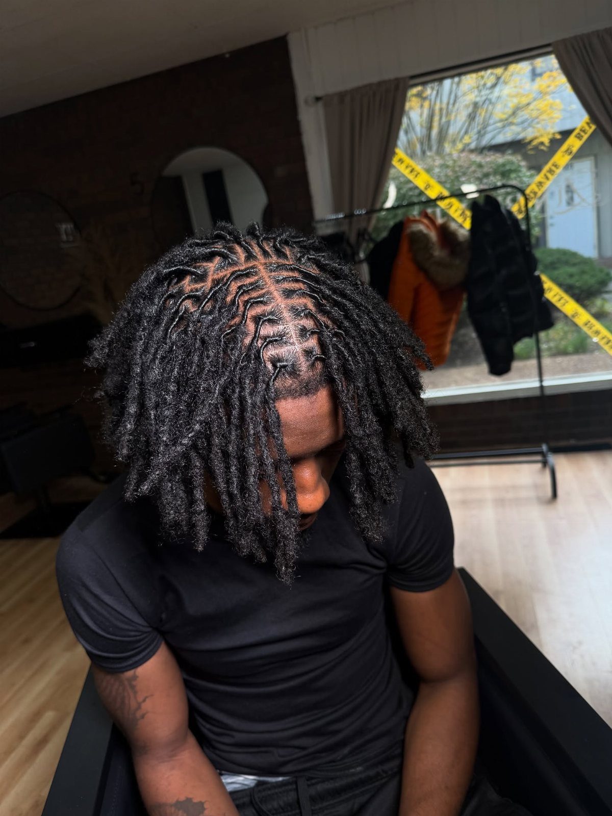 Man with locs braided into cornrows on top, falling around his face.