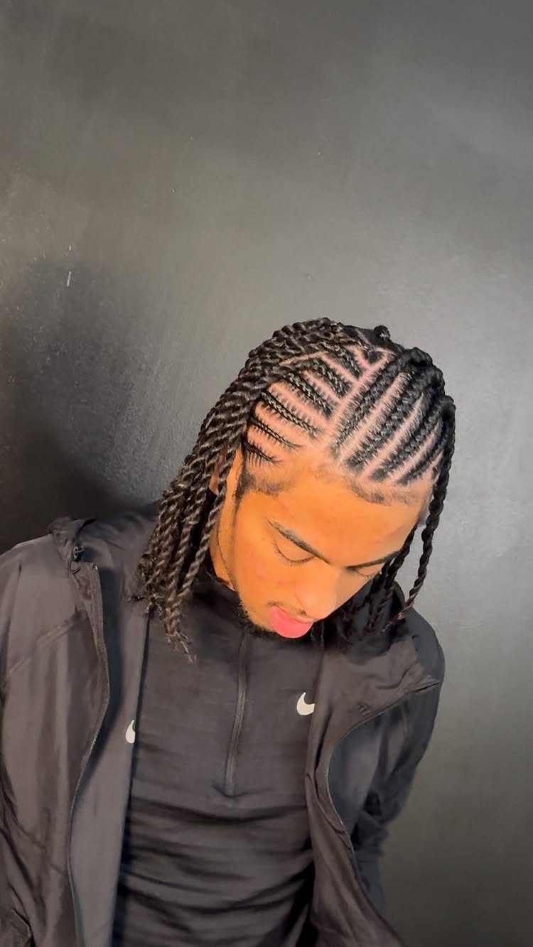 Young man with cornrows transitioning into twists wearing a black Nike jacket.