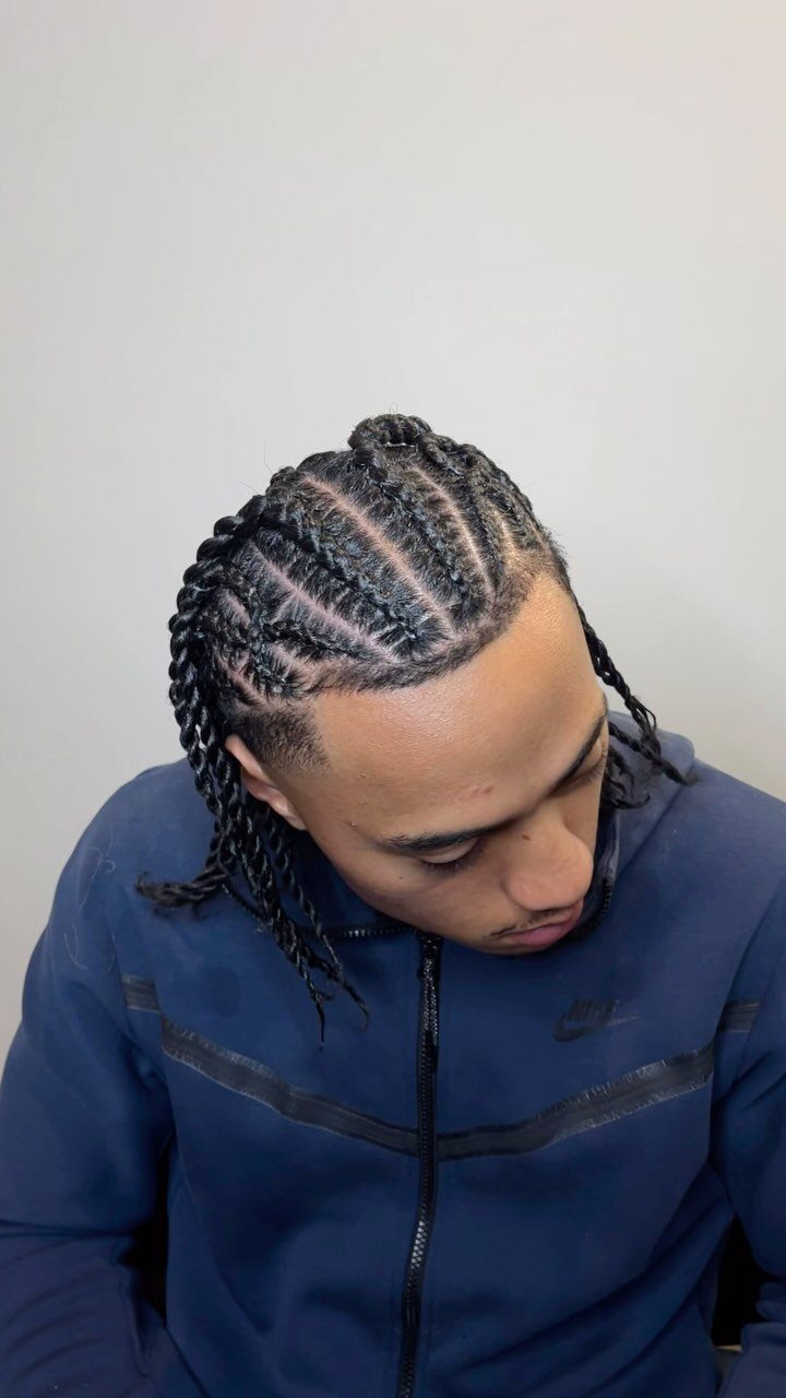Man with cornrows transitioning into twists at the ends wearing a navy hoodie.