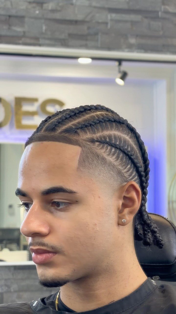 Young man with cornrows on top and a sharp taper fade on the sides.