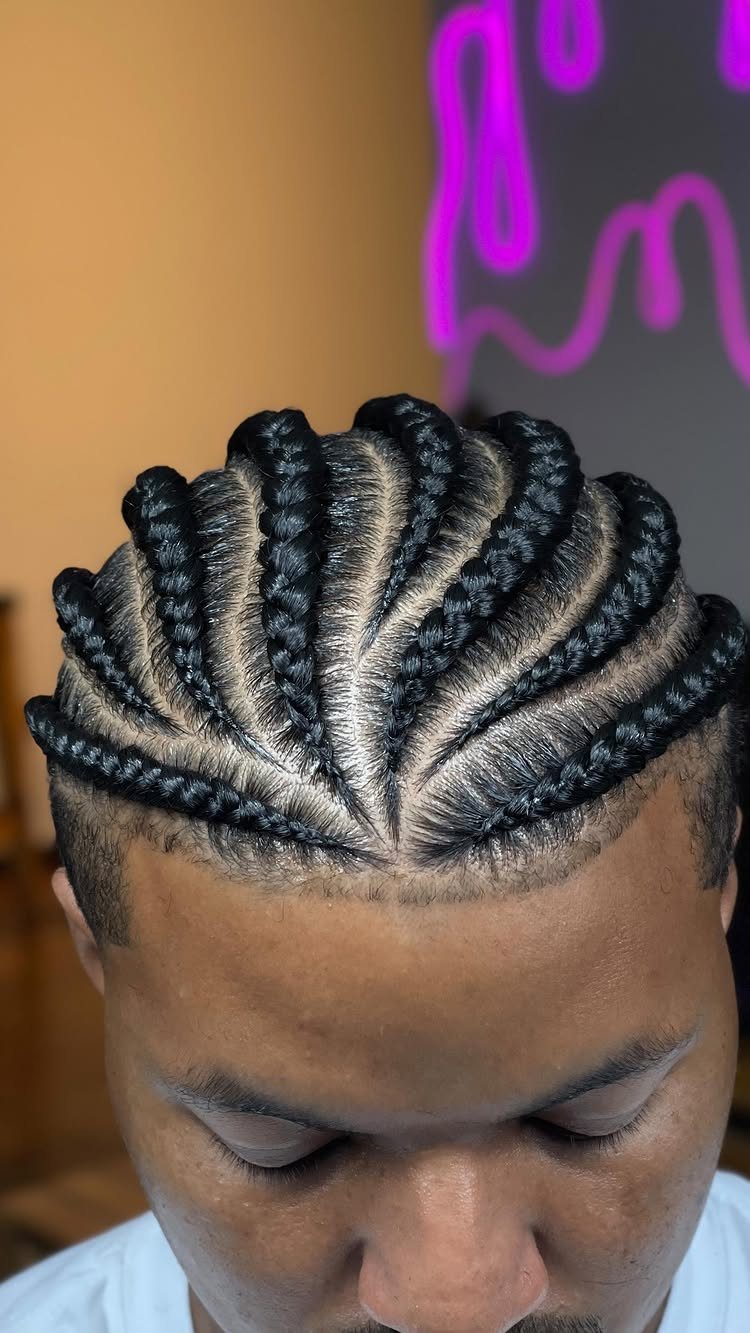 Man with thick jumbo cornrows braided across his head with clean parts.