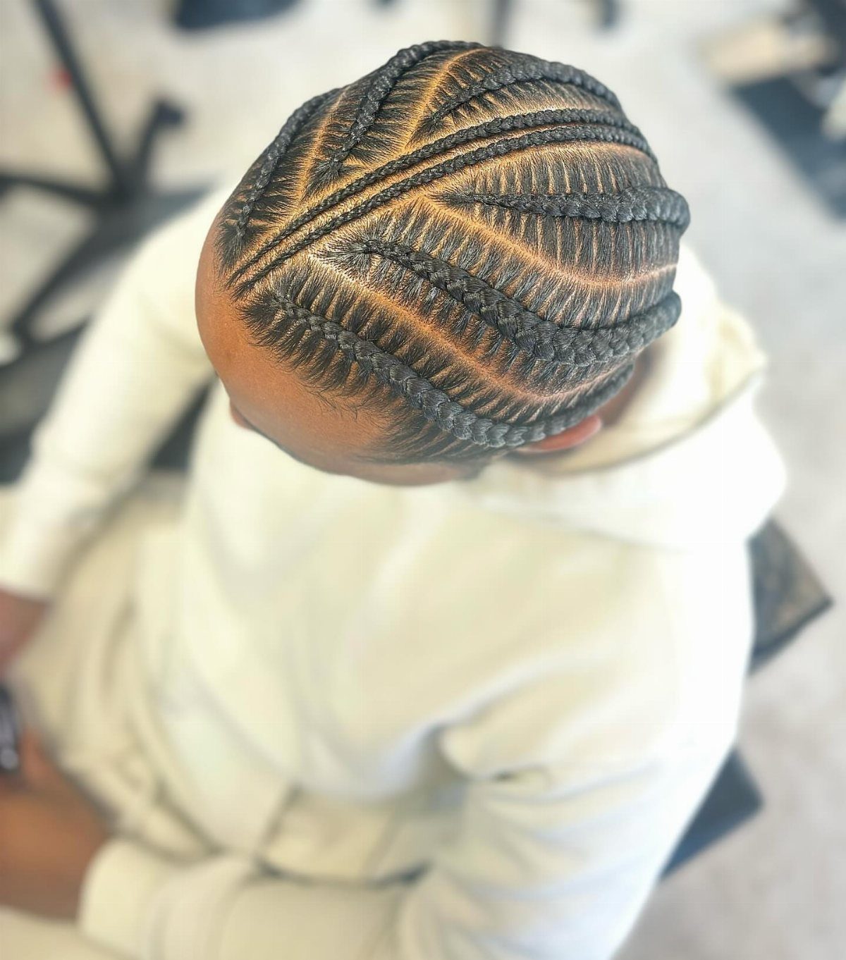 Intricate micro cornrows styled in a curved geometric pattern on a person's head.