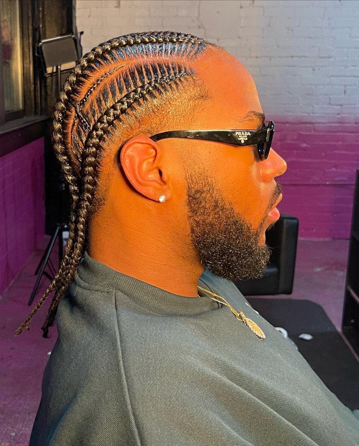 Man with a groomed beard wearing cornrows of multiple different sizes and widths.