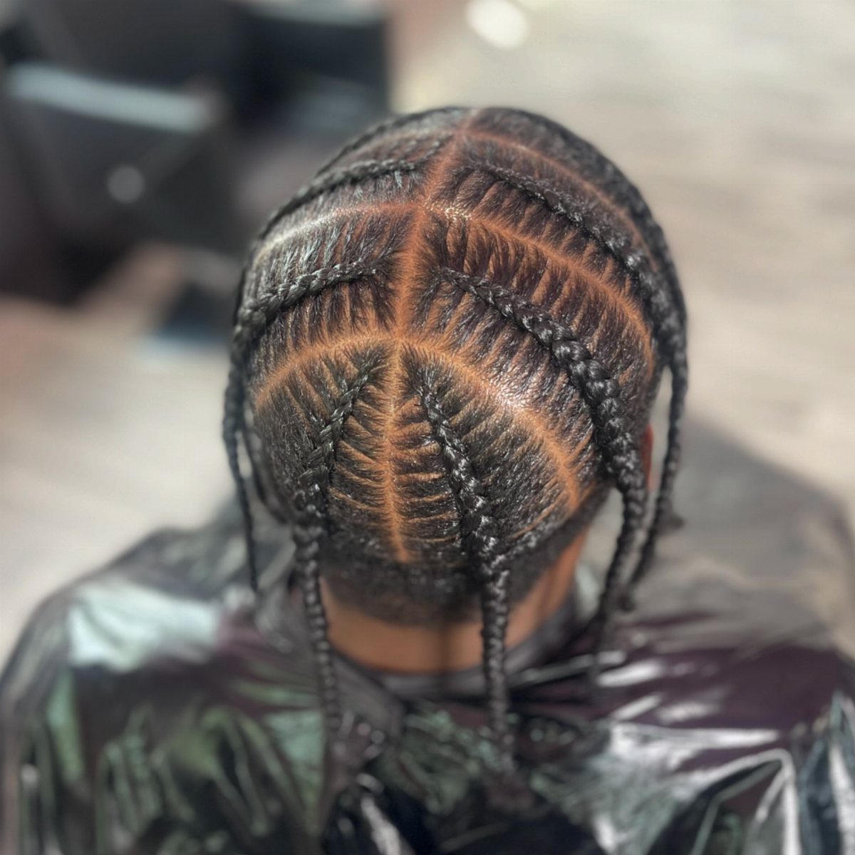 Symmetrical cornrow braids with a distinct middle part on a person's head.