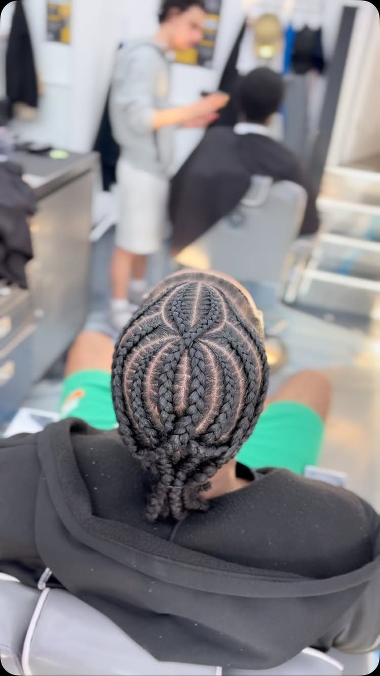 Spider cornrows radiating from the center of a man's head in a barbershop.