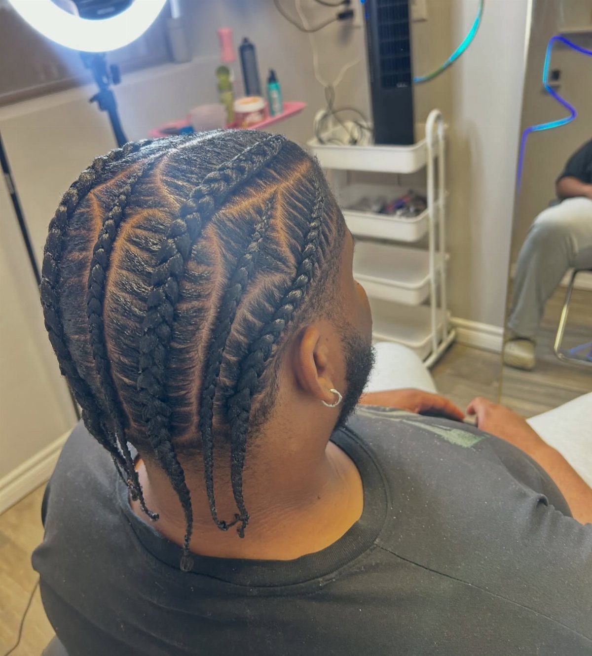 Man with straight-back cornrows featuring sharp zigzag parts between the braids.