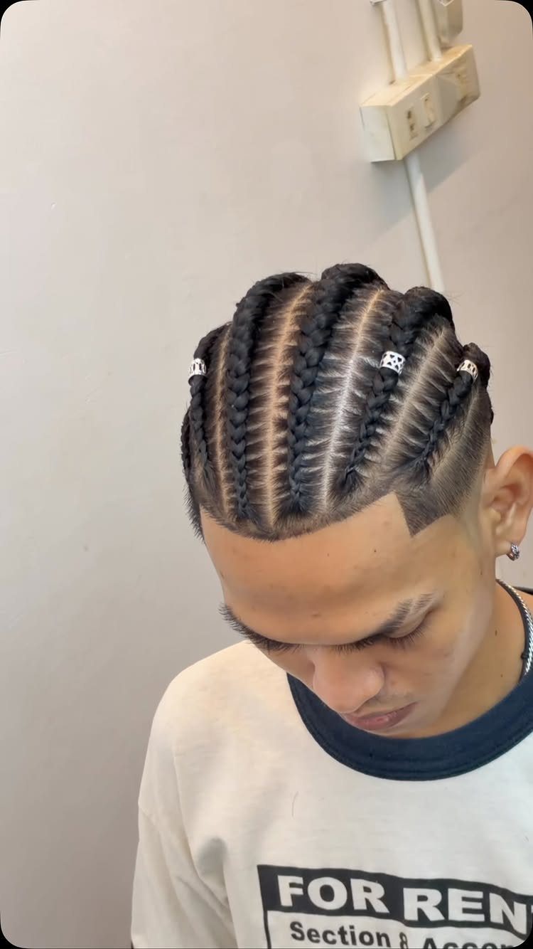 Man with cornrows on top and a shaved undercut with silver hair rings.