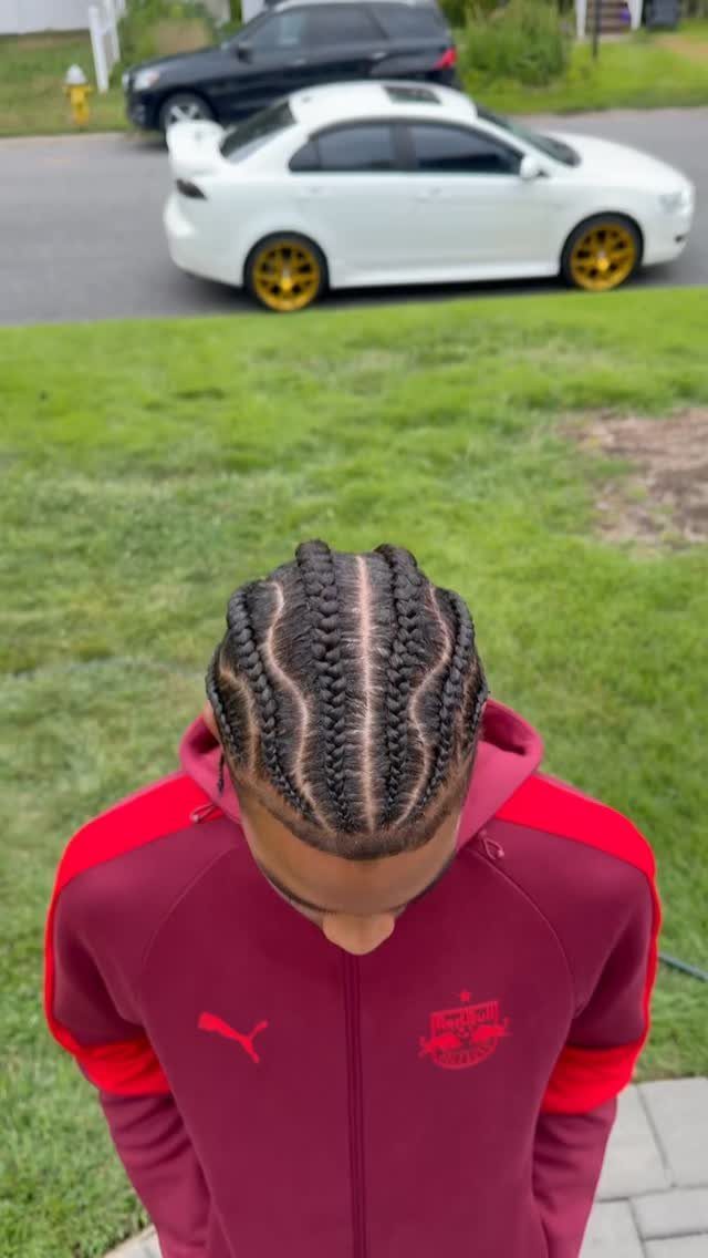 Man with cornrows featuring wavy parts wearing a maroon Puma hoodie outdoors.