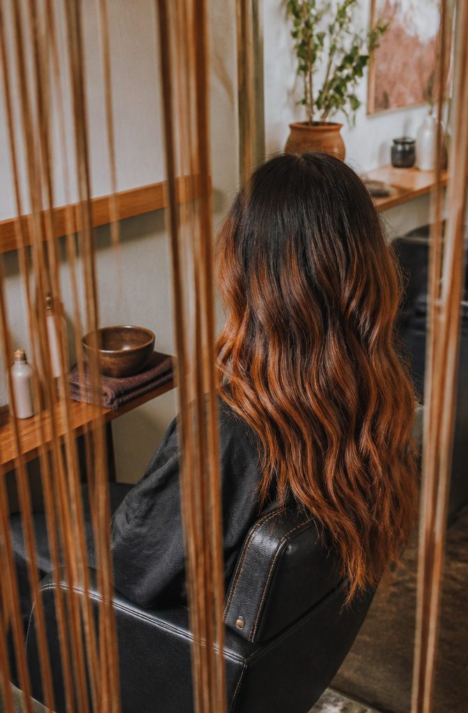 Long dark hair melting into hand-painted copper ribbons at the ends