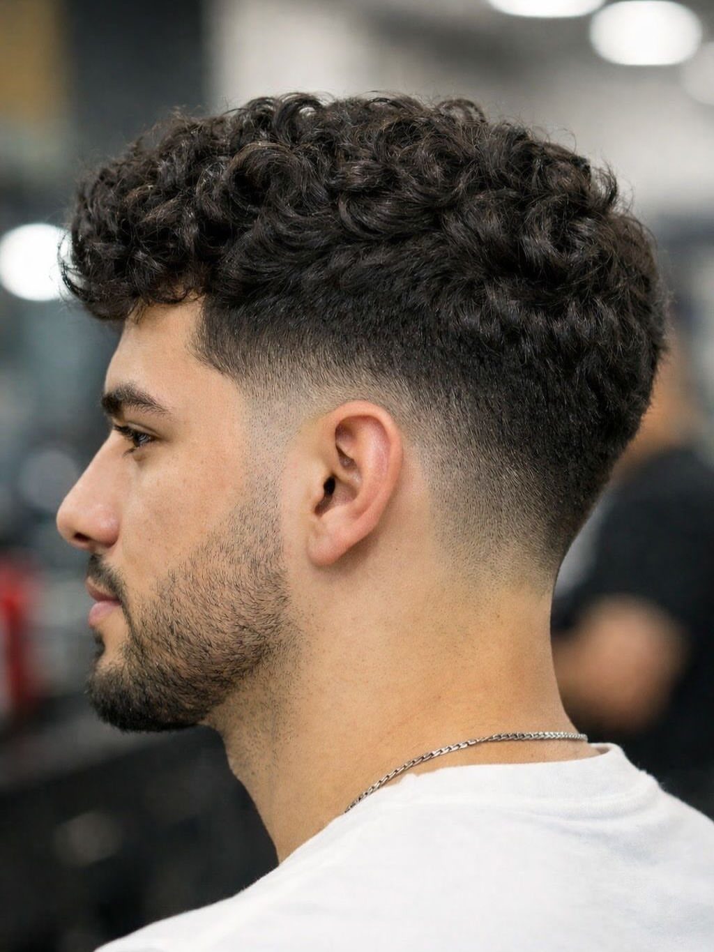 Man with curly hair on top and a clean skin fade haircut.