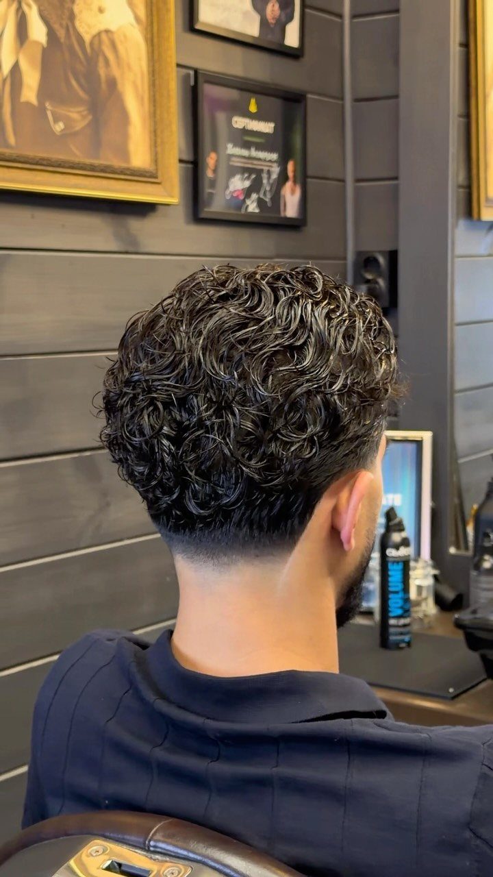Man with dark curly hair on top and a high taper fade haircut