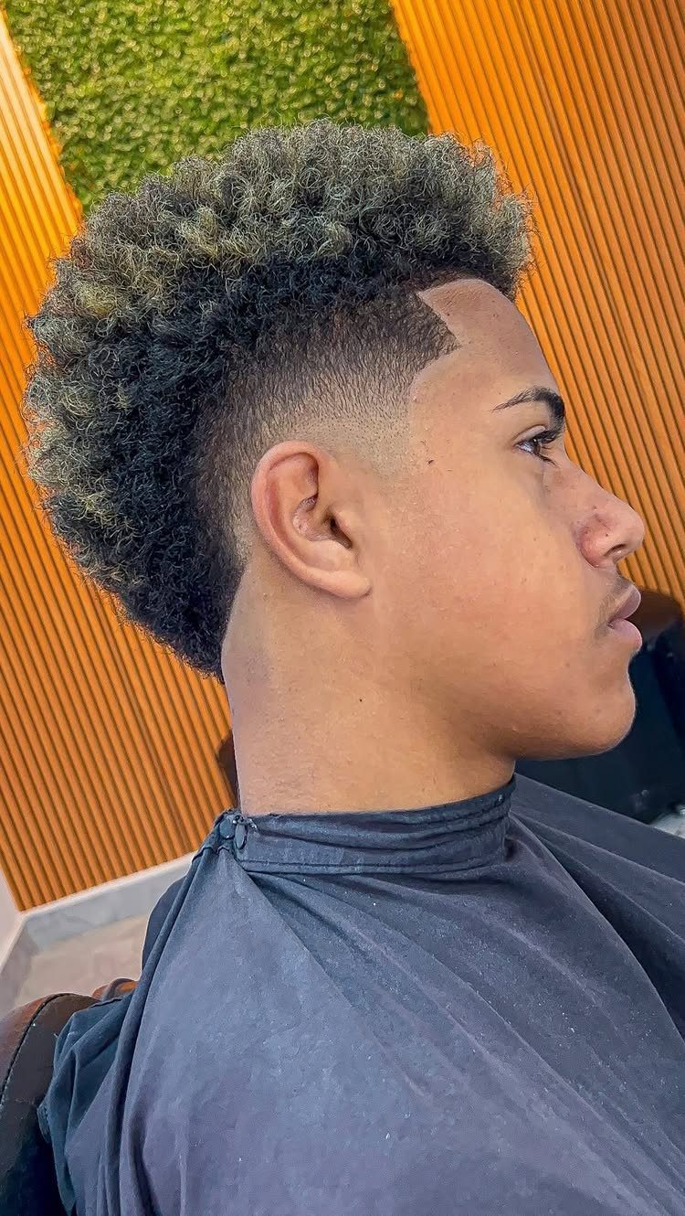 Young man with a curly mohawk haircut and faded sides in a barbershop.