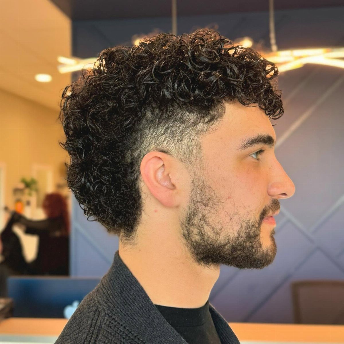 Man with a curly mullet haircut featuring short sides and long curly back.
