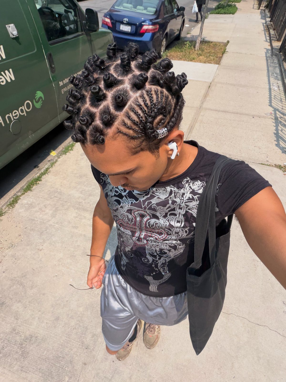 Man with short dreadlocks styled into Bantu knots and side braided rows.