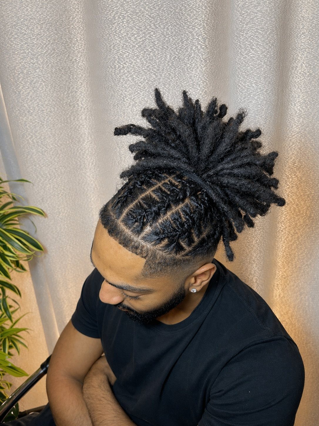 Man with barrel twists transitioning into short dreadlocks tied in a high bun.