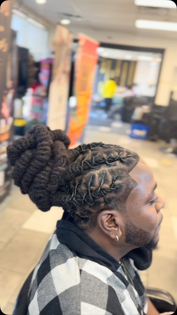 Man with dreadlocks woven into a basket-weave pattern and a large back bun.