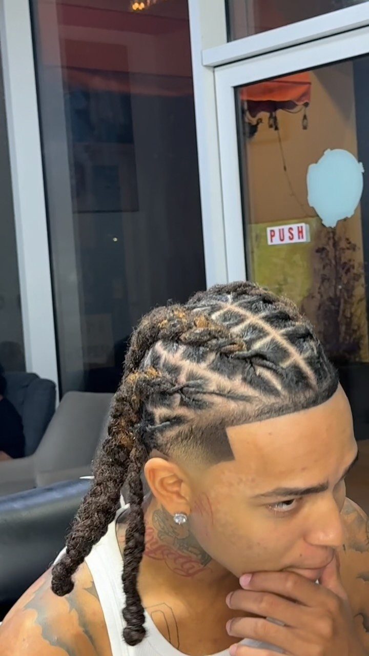 Man with braided dreadlocks in a criss-cross pattern and a sharp taper fade.