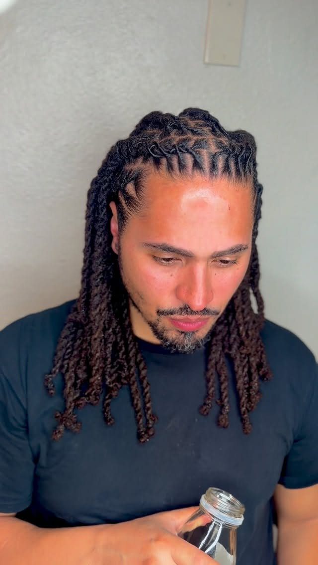 Man with long dark dreadlocks styled in braided rows at the scalp.