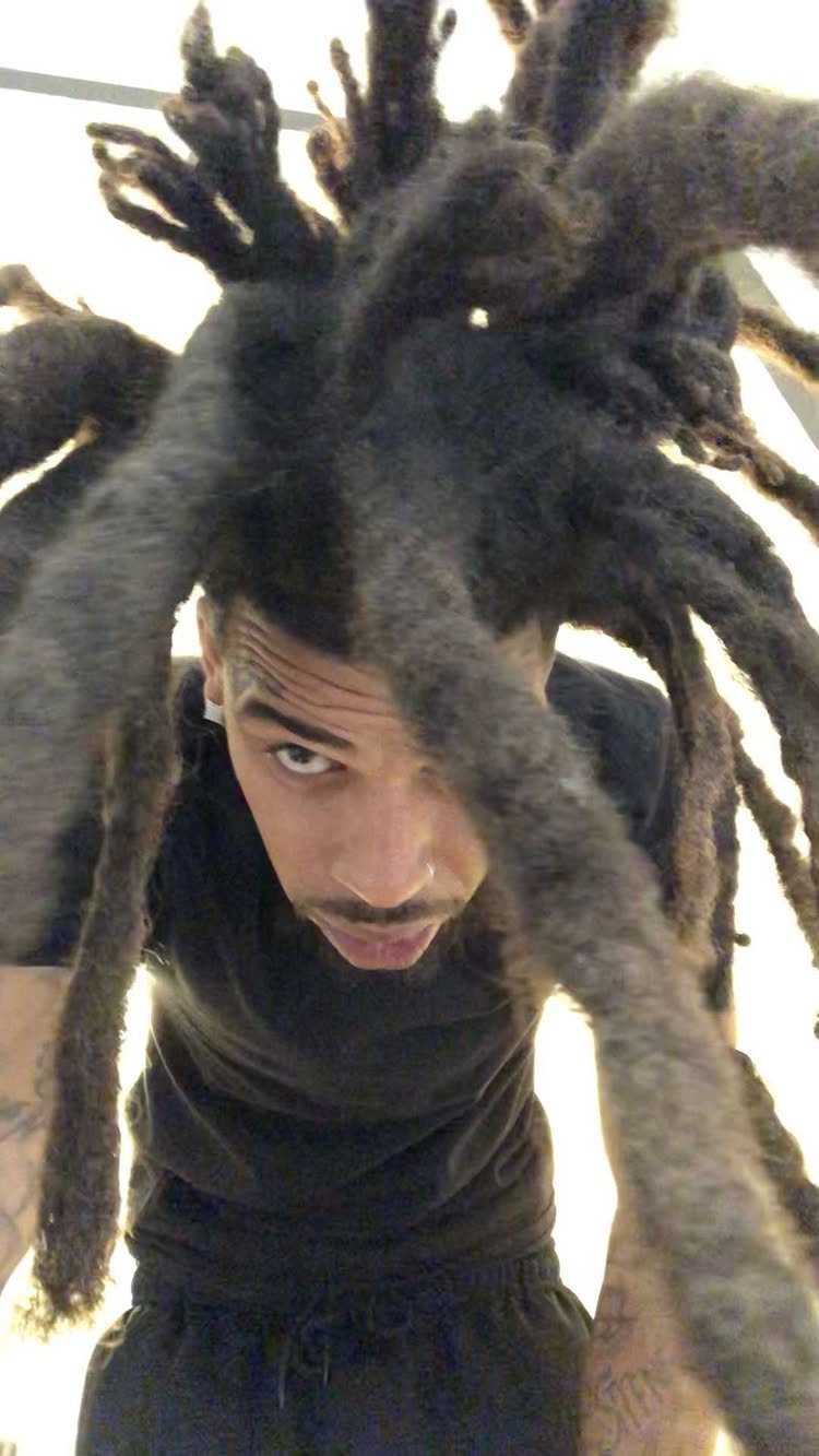 Man with long, thick freeform dreadlocks fanning out around his head.