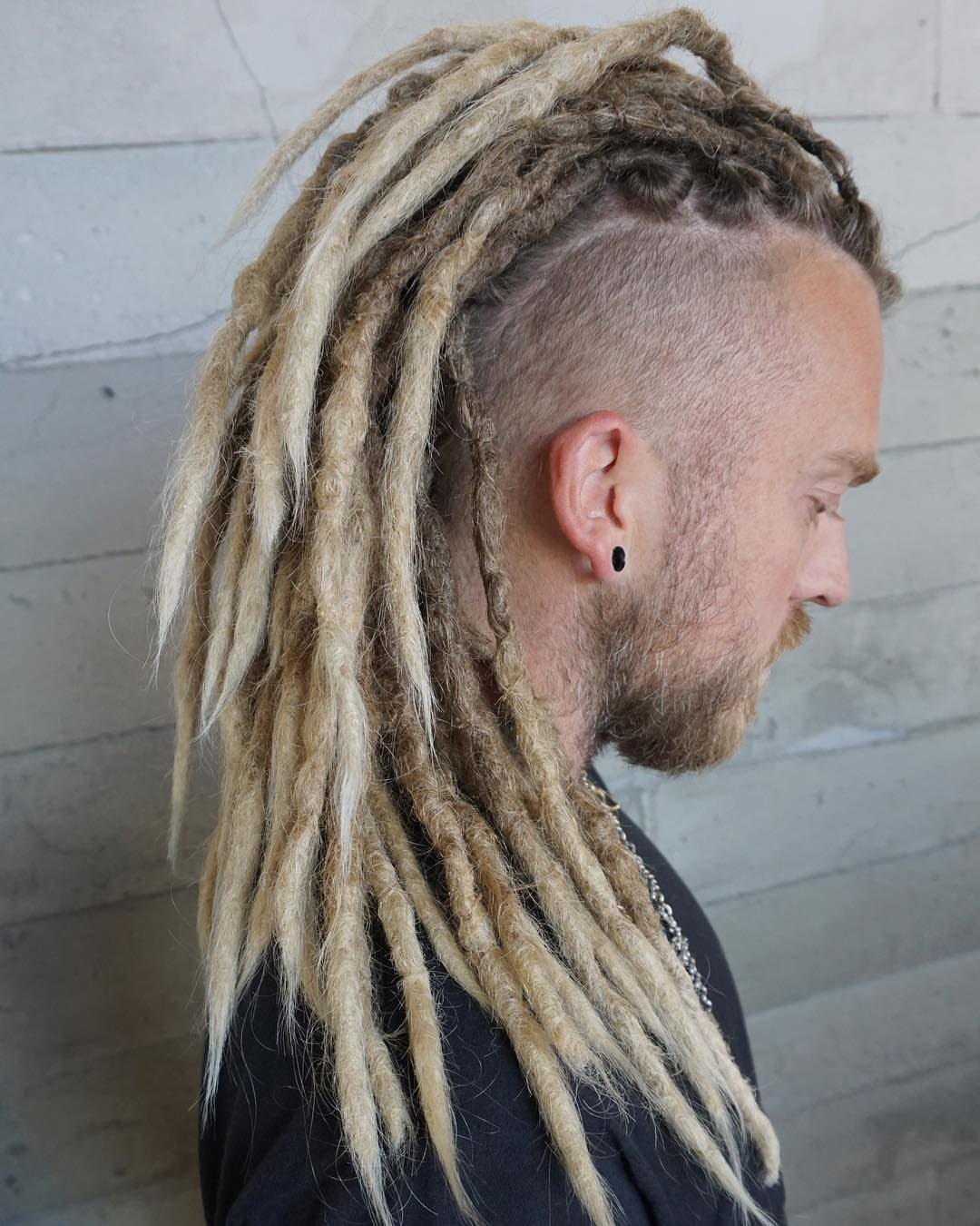 Man with long blonde and brown dreadlocks styled in a mohawk with shaved sides.