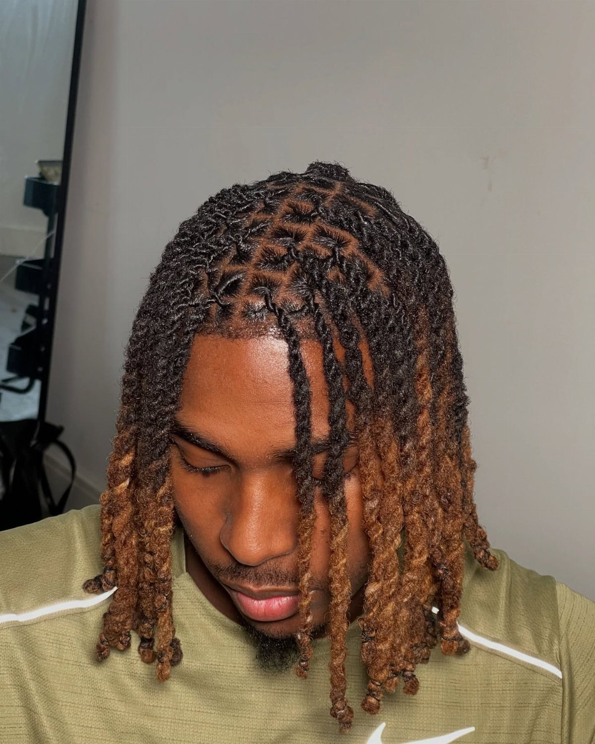 Man with ombre brown dreadlocks falling forward over his forehead and cheeks.