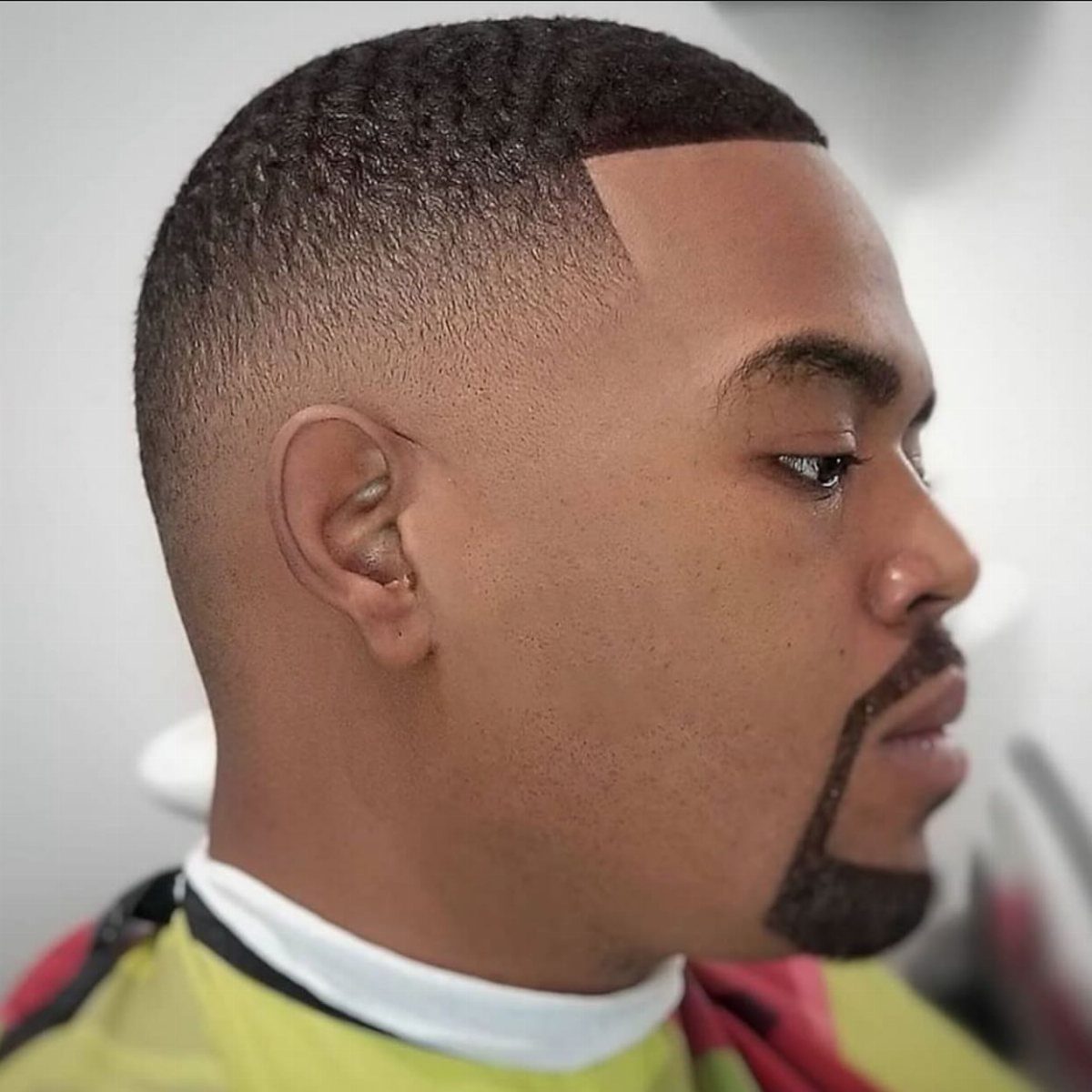 Man with a bald fade haircut and a neatly trimmed beard in profile.