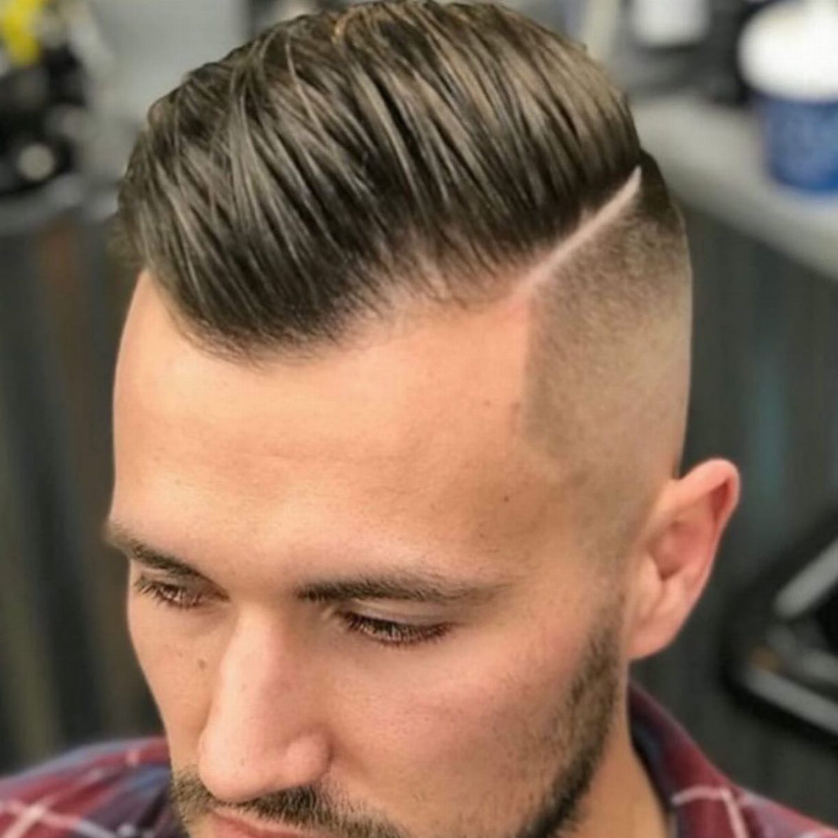 Man with a brown fade haircut and a shaved hard part line.