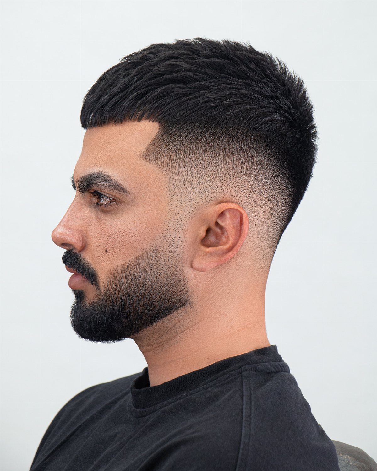 Man with a high skin fade haircut and a neatly trimmed black beard.
