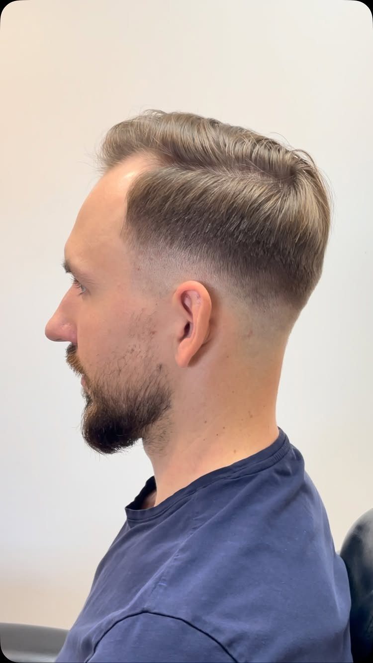 Man with a skin fade haircut and a sculpted beard in side profile.