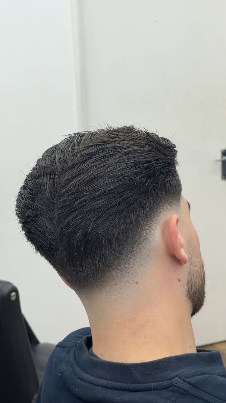 Man with a skin fade haircut and groomed beard seen from the side back