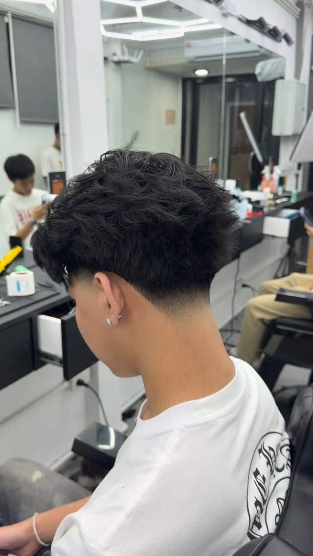 Man with wavy dark hair and a clean taper fade at the neckline.