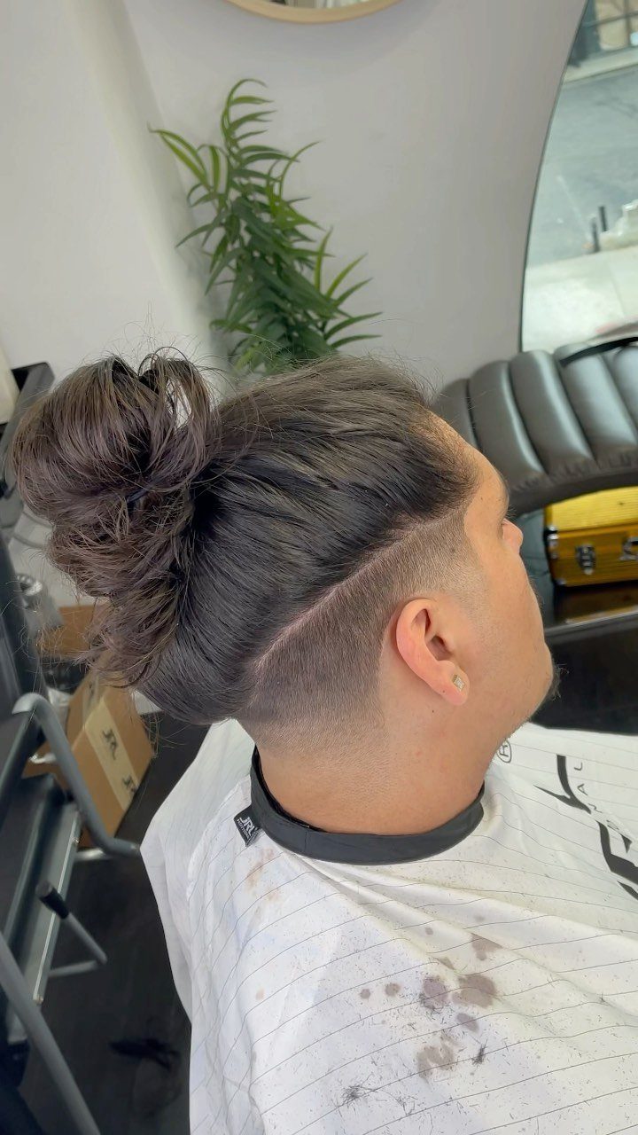 Man with a dark brown undercut fade and hair tied in a bun.