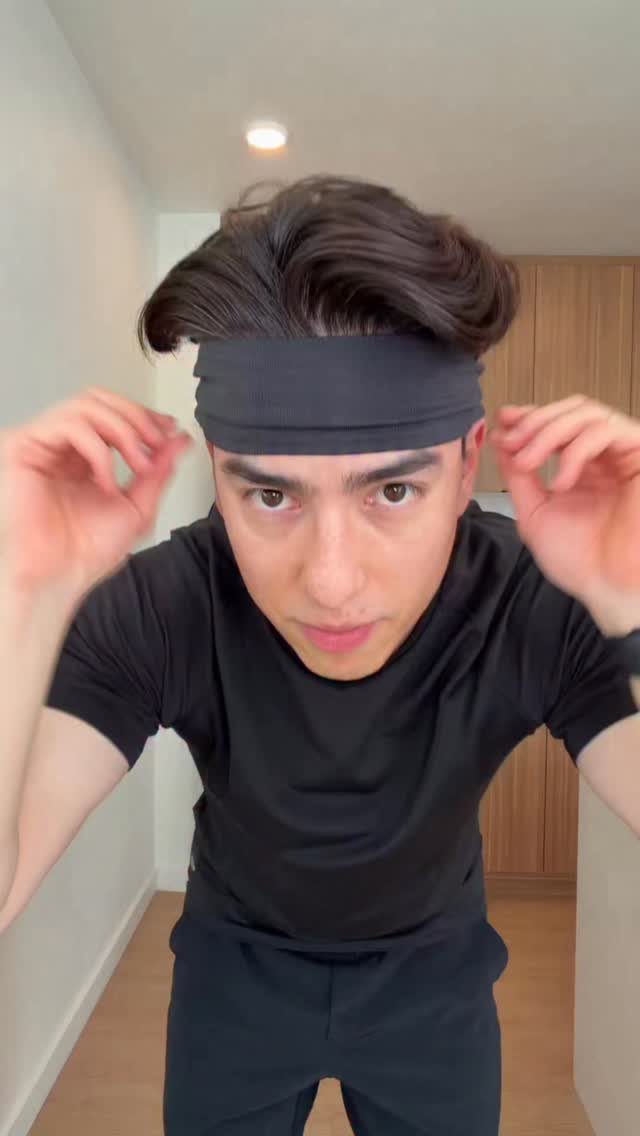 Man with long wavy brown hair held back by a black fabric headband.