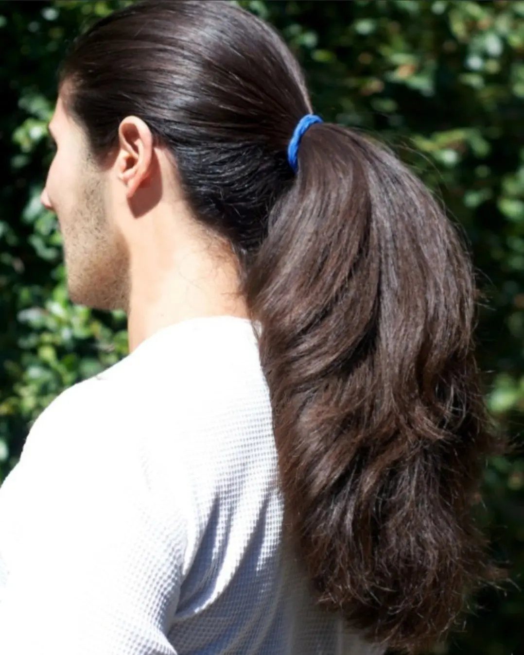 Man with long brown hair tied back in a ponytail with a blue band.