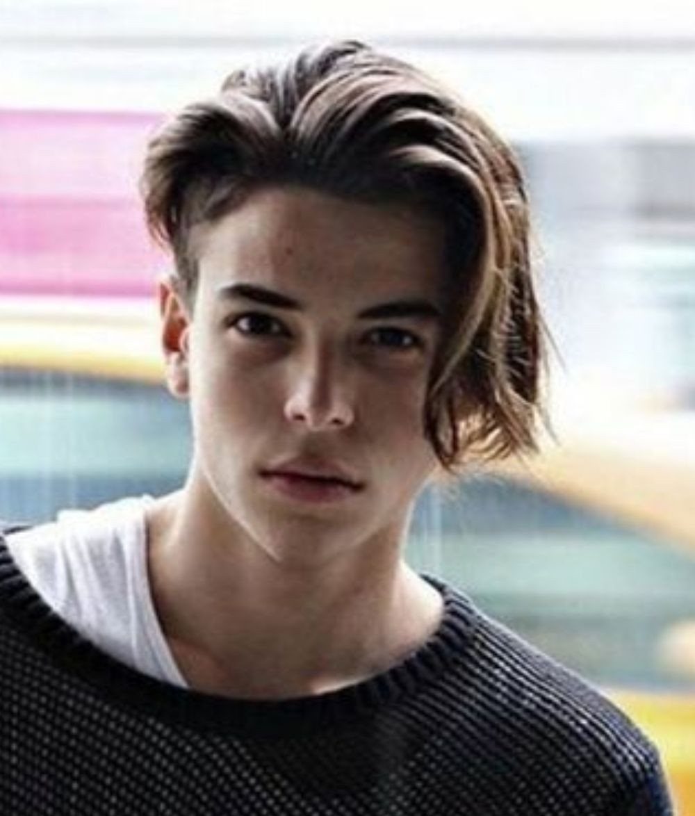 Young man with long brown hair swept back with a side part.